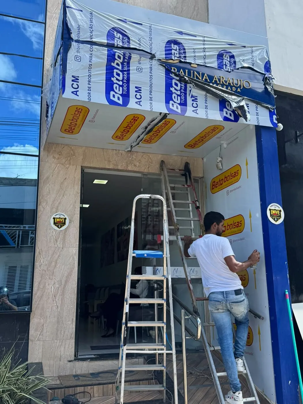Instalador da New Gráfica fixando ACM na fachada da Beto Bolsas